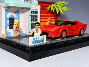 Eine LEGO-Szene mit einem roten Sportwagen, einem Schild mit 'MIAMI VICE', einer Palme und zwei Figuren vor einem farbenfrohen Gebäude.